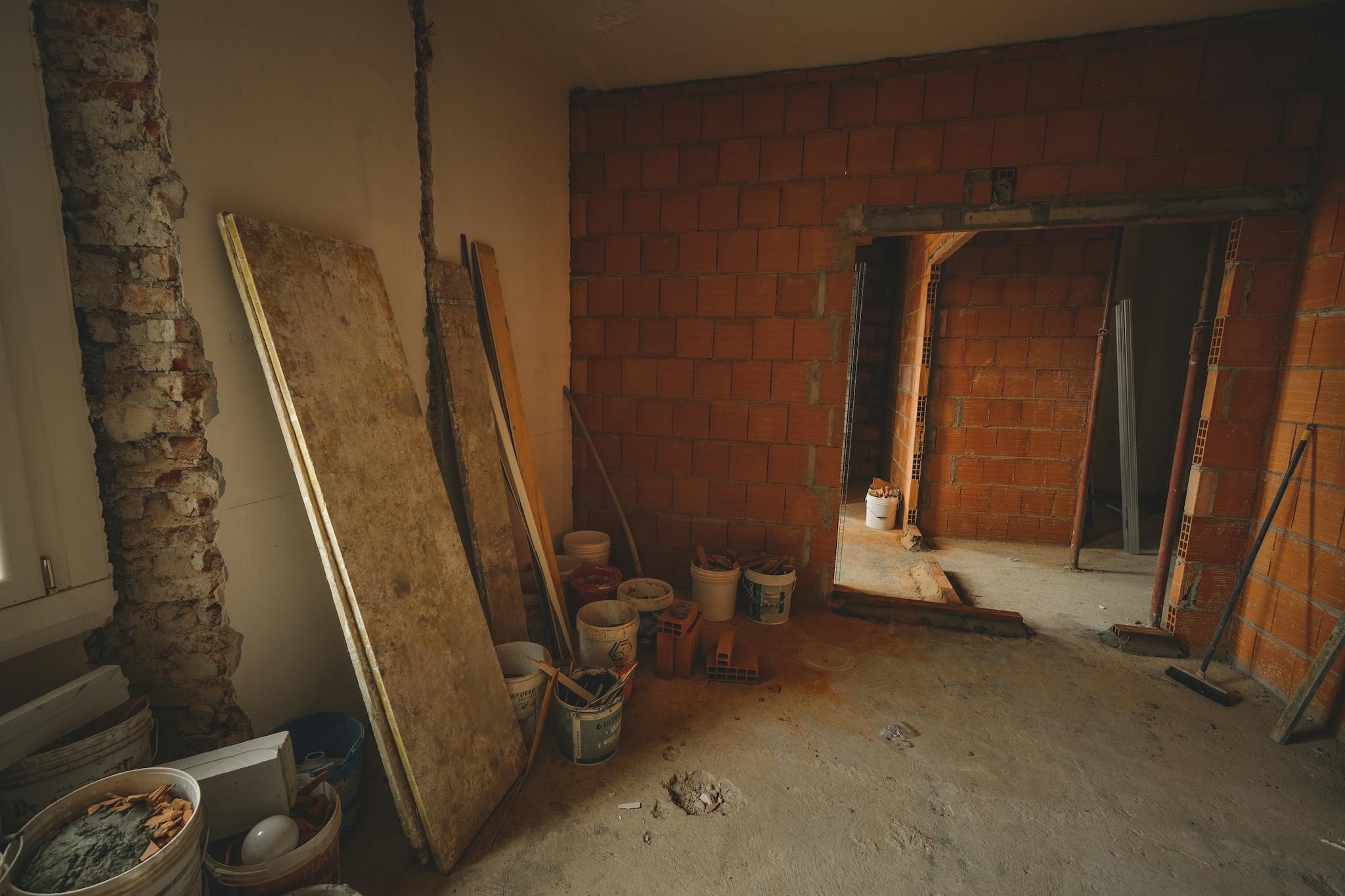A red brick wall under construction with tools and materials scattered around in a renovation project.