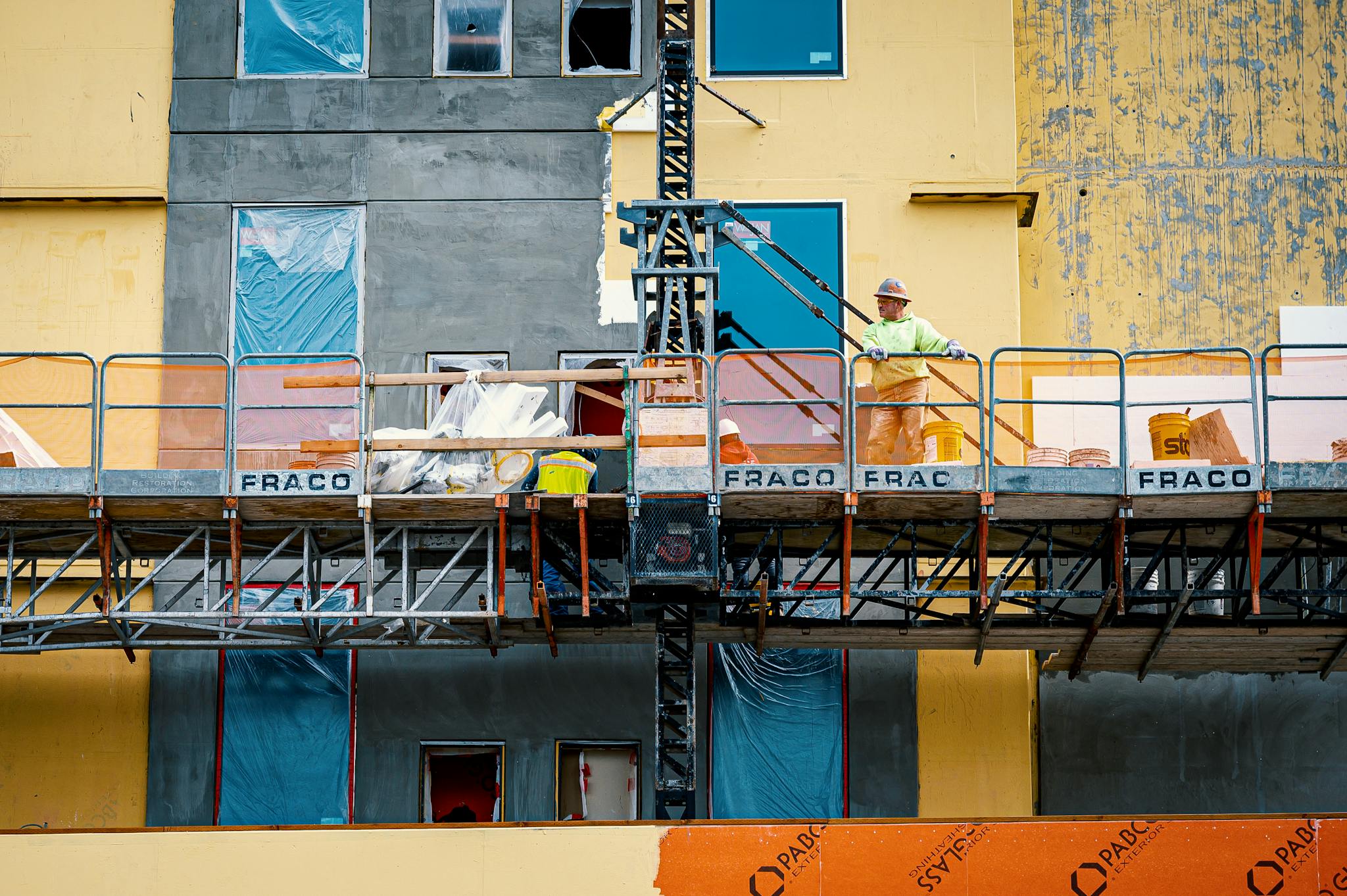 Construction worker on scaffolding during building facade renovation.