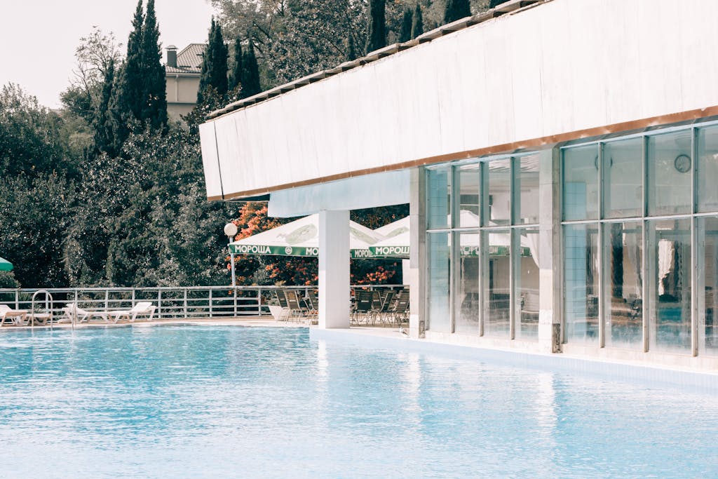 Stunning outdoor poolside view of a modern resort with glass windows reflecting summer sunlight.